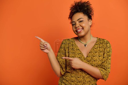 Foto de Elegante mujer afroamericana sonriendo y señalando algo. - Imagen libre de derechos