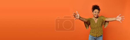 Photo for Man extends arms in front of vibrant orange background. - Royalty Free Image