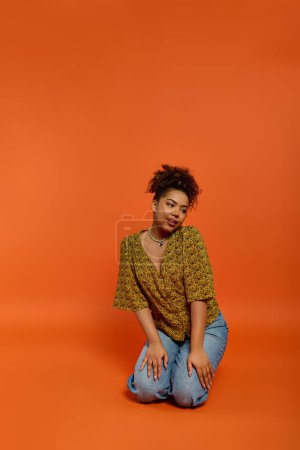 Stylish African American woman amidst vibrant orange backdrop.
