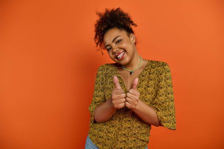 Photo for African American woman in stylish attire poses, making a peace sign with hands on vibrant backdrop. - Royalty Free Image