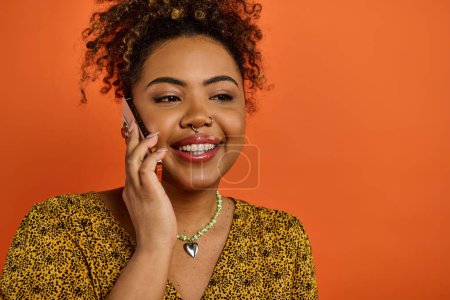 Photo for African American woman in stylish attire smiling while talking on cell phone. - Royalty Free Image