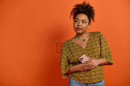 Stylish African American woman posing against bright orange backdrop.
