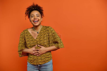 Photo for Stylish African American woman posing against vibrant orange backdrop. - Royalty Free Image