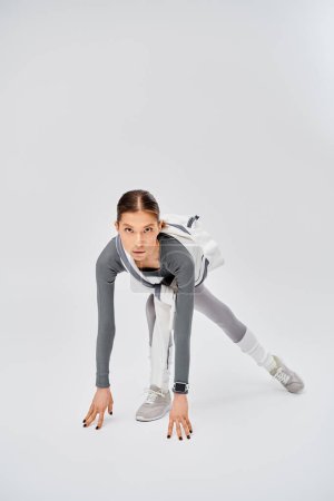 A sporty young woman in active wear showcases her strength and balance by performing a handstand on one leg.