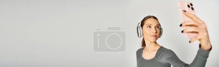 Photo for A sporty young woman in active wear holding a cell phone up to her face, engaged in a phone call. - Royalty Free Image