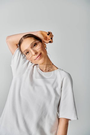 A young woman in a white shirt and glasses on a grey background, exuding elegance and style