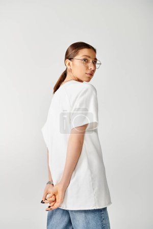 A young woman with glasses and a white shirt poses against a grey background.