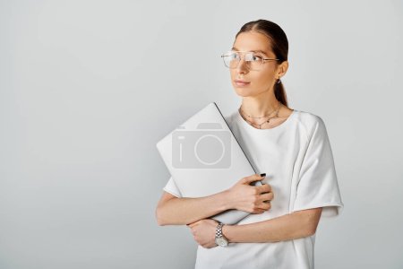 Foto de Mujer joven en gafas que sostiene el ordenador portátil, profundamente en el pensamiento, listo para anotar sus ideas e inspiraciones. - Imagen libre de derechos