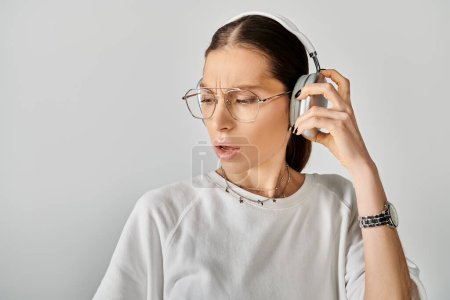 Eine junge Frau in weißem T-Shirt und Brille hört Musik