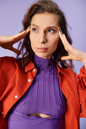Photo for A stylish young woman stands out in a purple top and a vibrant red jacket against a purple background. - Royalty Free Image