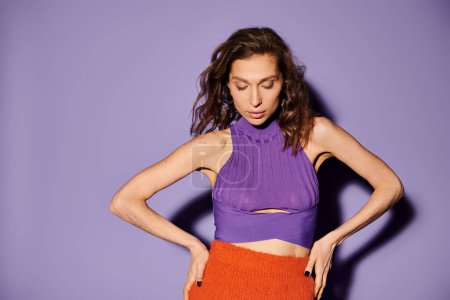 Photo for Stylish woman stunning in purple top and orange skirt against a striking purple backdrop. - Royalty Free Image