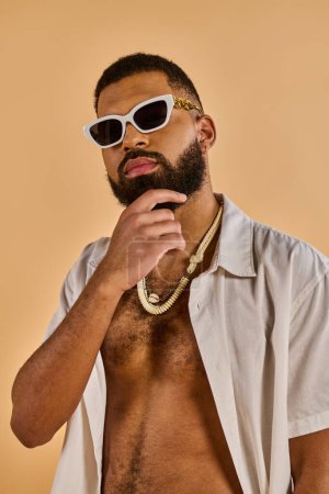 A man with a full beard is wearing sunglasses and a necklace, exuding a cool and confident demeanor as he stands tall.