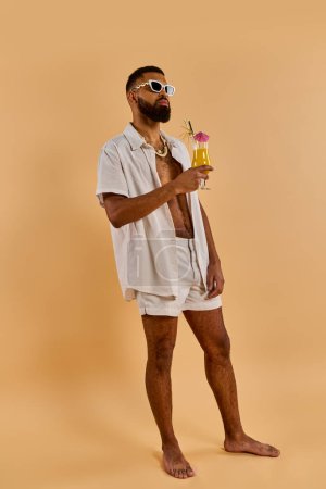 Un hombre con estilo en una camisa blanca y pantalones cortos disfruta de una bebida refrescante en un entorno sereno, exudando relajación y satisfacción.