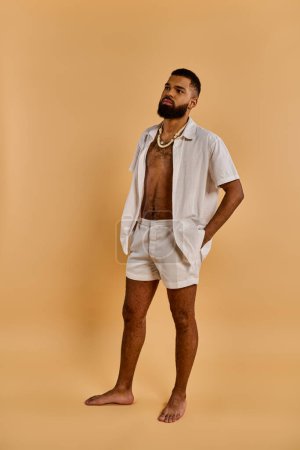 Photo for A man stands confidently in a white shirt and shorts, exuding a casual yet stylish aura. He gazes into the distance, radiating a sense of quiet confidence and ease. - Royalty Free Image