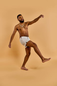 A shirtless man with a beard joyfully dances in the vast desert, moving to an unseen beat with his bare feet kicking up dust. Tank Top #706349574