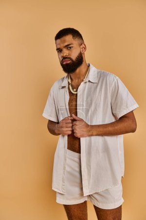 A stylish man with a beard is casually dressed in a white shirt and shorts, exuding a relaxed and laid-back vibe.
