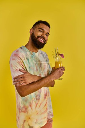 A man wearing a vibrant tie dye shirt is seen enjoying a drink. The colorful shirt adds a playful element to the scene.