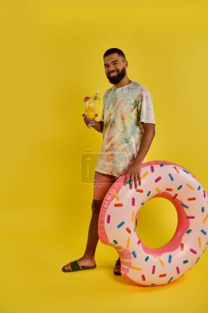 A man stands in awe next to a giant doughnut, dwarfed by its massive size. The doughnut is colorful and tempting, begging to be eaten.