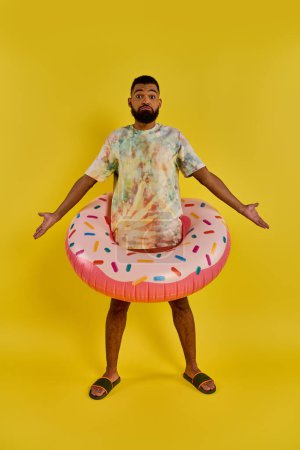 Ein stilvoller Mann im Krawattenhemd hält einen bunten Donut-Wagen, der inmitten einer sommerlichen Szene mit einer skurrilen Note steht..