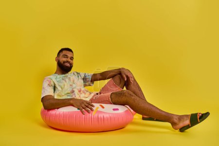 A man sits gracefully on a pink inflatable object, looking peaceful and content as he enjoys a moment of relaxation on the soft surface.