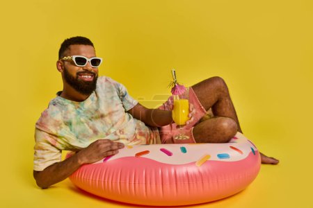 A man in a relaxed posture is sitting on the vibrant pink doughnut float, exuding a sense of calmness and leisure on the water.