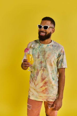 A stylish man in a tie dye shirt is leisurely holding a drink, exuding a laid-back and free-spirited vibe.