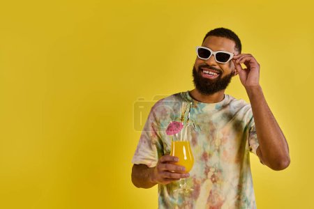 A stylish man in a tie dye shirt joyfully holds a glass of refreshing orange juice, showcasing a vivid and colorful scene.
