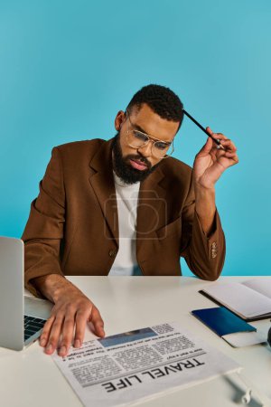 Téléchargez les photos : Un homme assis à une table, profondément absorbé dans son travail sur un ordinateur portable, tapant loin, entouré d'une mer de papiers et de stylos. - en image libre de droit