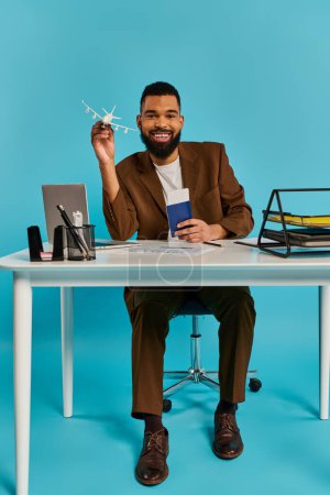 Un homme est assis à un bureau, concentré sur son écran d'ordinateur portable. Il tape et parcourt, entouré d'un espace de travail rempli de papiers et de fournitures de bureau.