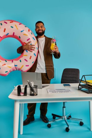 Ein Mann mit freudigem Gesichtsausdruck hält in der einen Hand einen riesigen, köstlichen Donut, während er in der anderen ein erfrischendes Getränk balanciert.