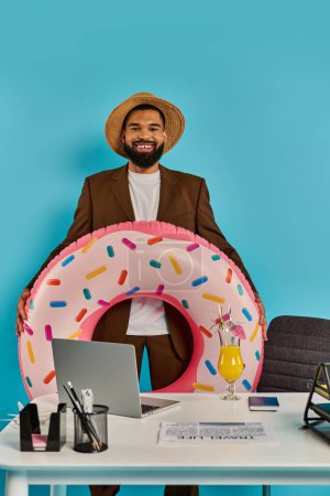 Un homme assis à un bureau avec un donut géant en face de lui, l'air intrigué et excité.