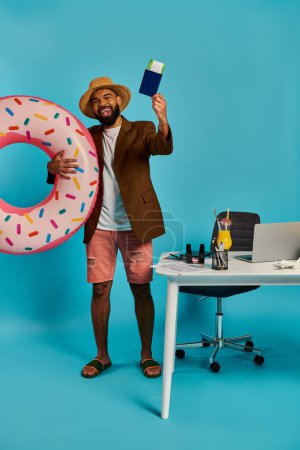 A man is holding a giant donut in one hand and a book in the other, appearing absorbed in reading while enjoying his sweet treat.