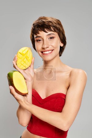A young woman in a red top holding mangos.