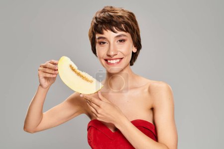 Photo for A young woman in a striking red dress posing with melon. - Royalty Free Image