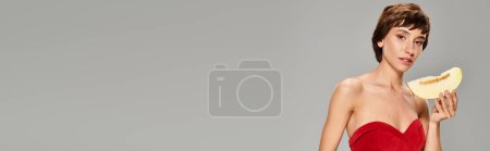 Téléchargez les photos : Une femme élégante dans une robe rouge tenant gracieusement la mangue. - en image libre de droit