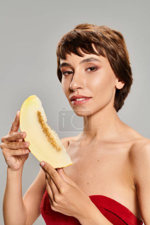 Photo for A captivating young woman in a bright red dress posing with a ripe mango. - Royalty Free Image