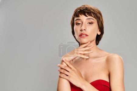 Eine junge Frau steht selbstbewusst in einem roten Kleid vor einer lebendigen Kulisse.