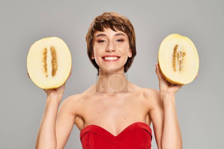 Photo for Elegant woman in red dress holds two melon slices. - Royalty Free Image