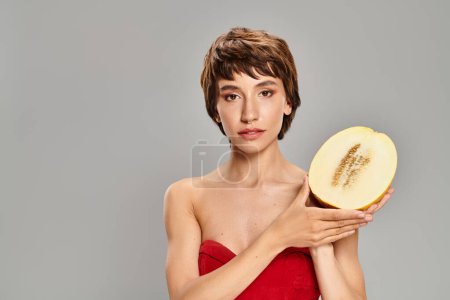 A woman in a red dress seductively holds an apple.