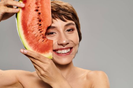 Photo for Young woman joyfully holds watermelon slice to her face. - Royalty Free Image