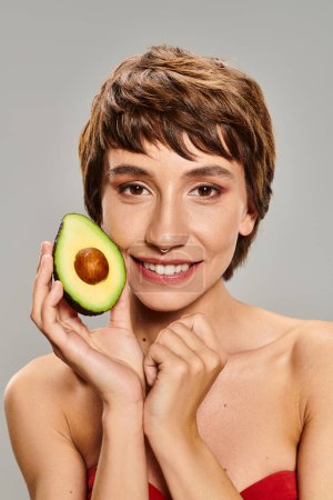 Photo for Young woman holding avocado in front of her face. - Royalty Free Image