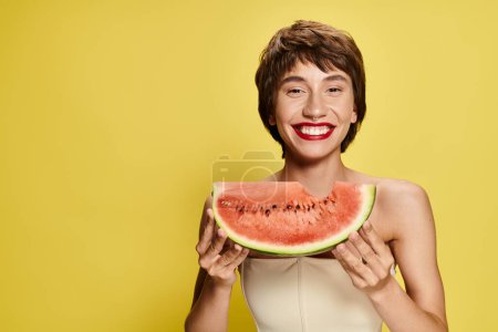 Photo for Young woman playfully holds a watermelon slice in front of her face. - Royalty Free Image