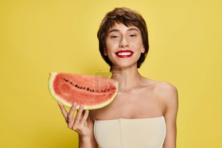 Young woman holding watermelon slice in front of her face.
