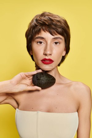 Woman playfully holds avocado in front of her face.
