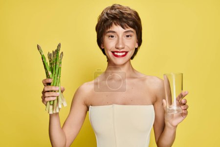 Photo for Graceful woman in white dress holding asparagus and glass. - Royalty Free Image