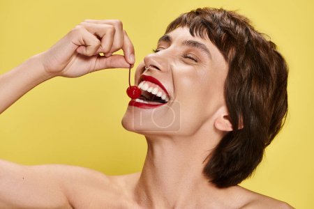 Foto de Mujer joven posando sensualmente con una cereza en la boca. - Imagen libre de derechos