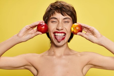 A man playfully holds two peaches.