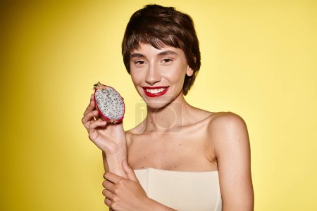 Woman in a white dress holding a dragon fruit.