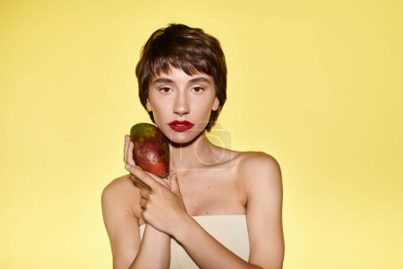 Foto de Una joven sosteniendo juguetonamente un trozo de fruta frente a su cara. - Imagen libre de derechos