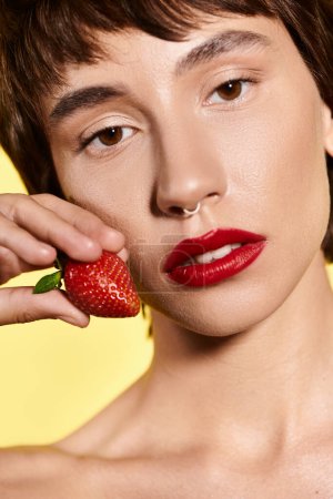 Téléchargez les photos : Une jeune femme tient délicatement une fraise vibrante dans sa main. - en image libre de droit